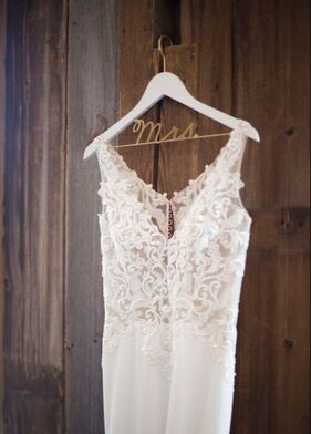 Close up of a wedding gown hanging against a barn wall